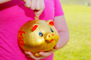Girl Purring Money Into Piggy Bank 